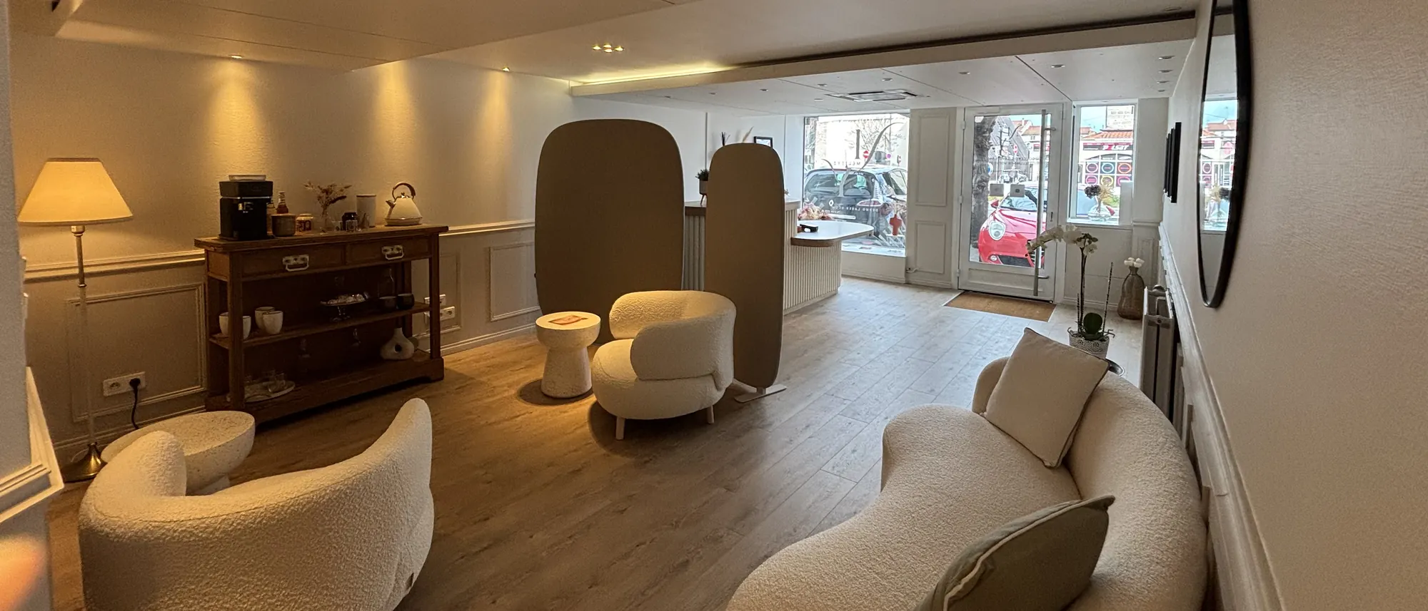 Le salon : canapé courbe, fauteuils bouclette, console à café et lumière de la vitrine